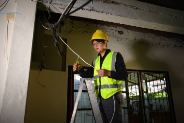Elektrik teknisyeni tavan altyapısı yakınındaki kabloları kuruyor veya onarıyor.