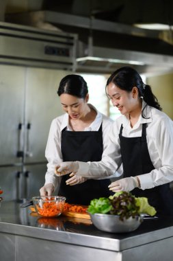 Gülümseyen aşçılık öğrencileri yemek kursunda sebze hazırlıyorlar..