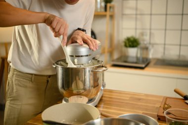 Genç Asyalı adam modern bir mutfakta çırpılmış krema yapmak için karıştırıcı kullanıyor..