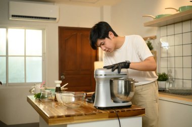 Genç Asyalı adam, mutfak mutfağında çırpılmış krema hazırlıyor..