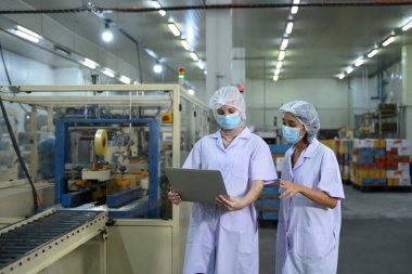 Gıda fabrikası personeli gıda paketleme tesisinde üretim verilerini inceliyor..