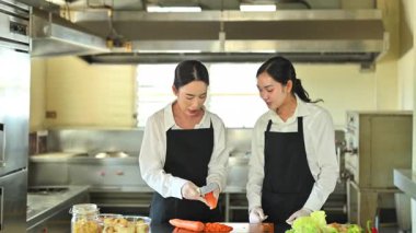 Aşçılık dersi sırasında taze sebzelerle yemek hazırlama teknikleri öğreten kadın aşçı..