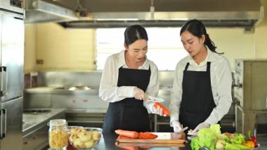 Aşçılık öğretmeni, profesyonel bir mutfakta havuç dilimlemeyi öğretiyor..