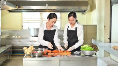 Şef üniforması giyen bayan öğrenci aşçılık kursunda sebze hazırlama teknikleri öğreniyor..