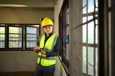 Konut inşaatını denetlemek ve yönetmek için dijital tablet kullanan site yöneticisi.