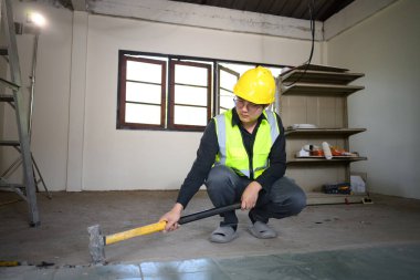 Yenileme projesi sırasında fayansları değerlendiren ve kıran inşaat denetçisi.