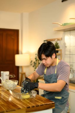 Asyalı adam sıcak bir mutfakta tereyağını elle şekillendiriyor..