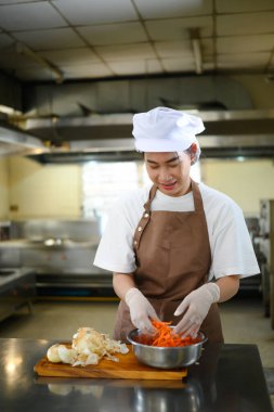 Gülümseyen öğrenci şef aşçılık kursunda malzemeleri hazırlıyor..