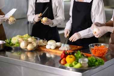 Aşçılık eğitimi sırasında soğan soyan ve dilimleyen öğrenciler.