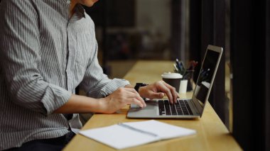 Modern kafede dizüstü bilgisayarla çalışan erkek serbest çalışanın yan görüntüsü.