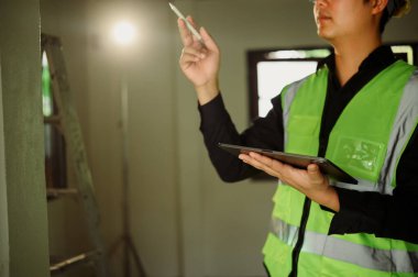 Yenileme sahasında proje ilerlemesini değerlendiren dijital tabletli inşaat denetçisi.