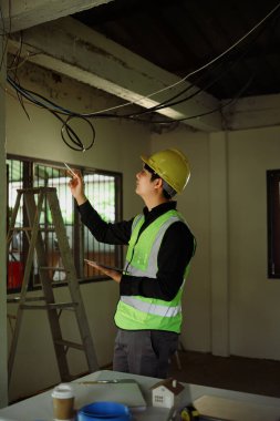 Bitmemiş bir odada tavan kurulumunu değerlendiren inşaat denetçisi.