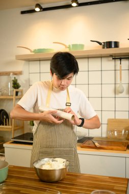 Asyalı erkek fırıncı depolama için krem şanti paketliyor.