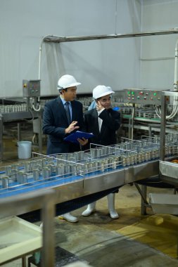 İş adamları, modern bir işleme tesisinde gıda üretim hattını inceliyorlar..