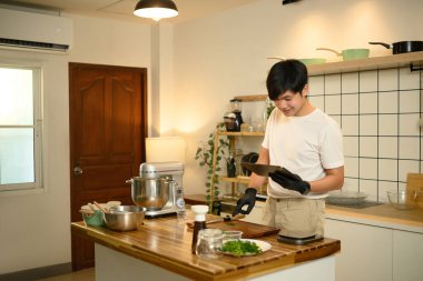 Mutfak adasının yanında krem şanti yapmaya hazır taze malzemelerle dijital tablet kullanan bir adam..