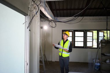 Bitmemiş bir odada tavan kurulumunu değerlendiren inşaat denetçisi.