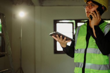 Güvenlik teçhizatındaki bölge amiri dijital tablet tutuyor ve telefonda konuşuyor..