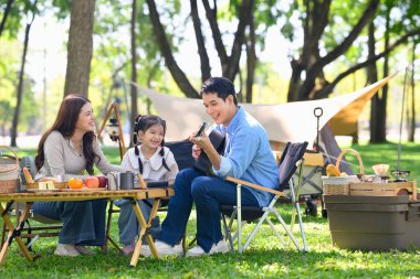 Mutlu bir aile ormanlık bir kamp alanında rahatlıyor ve eğleniyor..