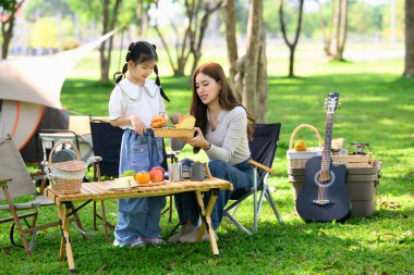 Anne ve kızı kamp alanında kahvaltı hazırlıyorlar..