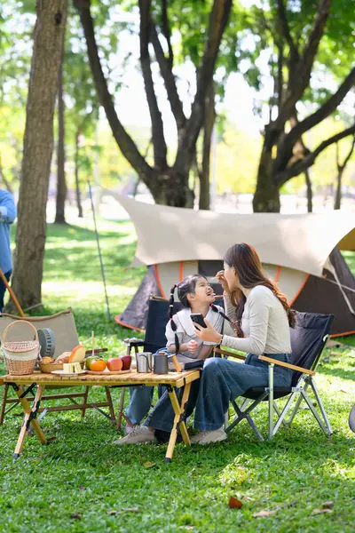 Mutlu anne, güler yüzlü kızını bir aile kahvaltısı sırasında dışarıda besliyor..