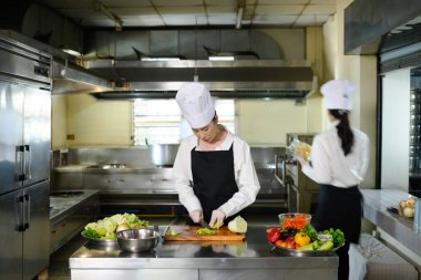 Profesyonel bir mutfakta sebze kesme eğitimi alan aşçılık öğrencisi..