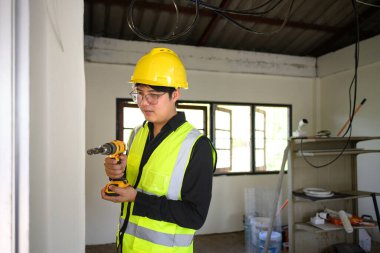 Konut sahasında elektrikli matkap kullanan inşaat işçisi..