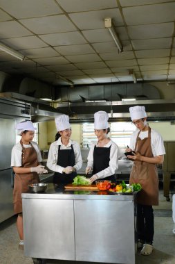 Aşçılık eğitmeni aşçılık dersleri sırasında öğrencilere dilimleme tekniklerini gösteriyor..