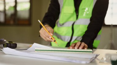 Bir mimar inşaat planı için kesin ölçümler yapmak için cetvel kullanıyor..