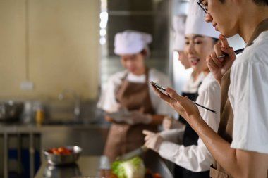 Aşçılık öğrencileri aşçılık kursunda bir yemek tarifi planı üzerinde çalışıyorlar..
