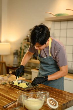 Genç adam ahşap mutfak tezgahında ev yapımı tereyağı yapıyor..