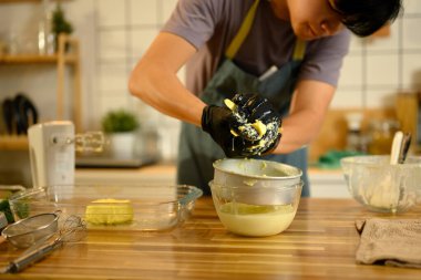 Eldivenli eller kremalı tereyağını kasenin üzerine sıkıyor, taze tereyağı bırakıyor..