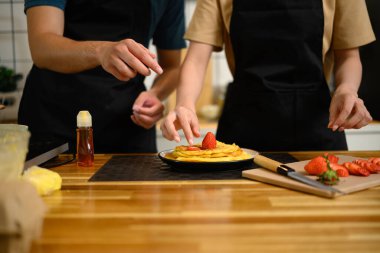 Sıcak bir mutfakta çilekli krep yapan çift..