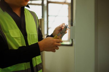 Elektrikçi yenileme alanında elektrik tellerini sökmek için tel kesici kullanıyor..