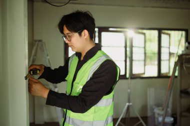 Bölge müfettişi yenileme veya elektrik tesisatı için duvar ölçüleri alıyor.