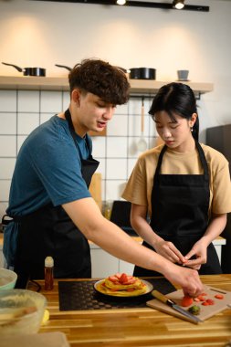 Mutfakta taze çilekle kaplanmış krep hazırlayan mutlu çift..