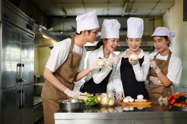 Aşçılık dersinde genç aşçılar işbirliği yapıyor ve gülümsüyor..