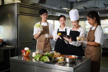 Aşçılık okulu eğitmeni bir grup aşçılık öğrencisine ders sırasında rehberlik ediyor..