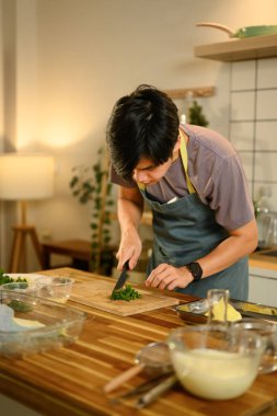 Mutfakta tereyağı yapmak için tahta kesme tahtasında taze otlar hazırlayan bir adam..
