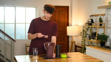 Kafkasyalı genç adam sıcak bir ev mutfağında protein içeceği hazırlıyor..