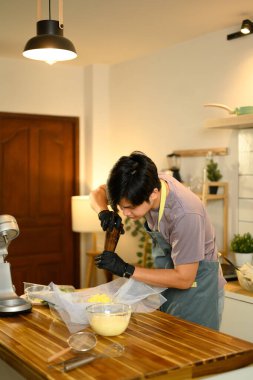 Ev mutfağında taze tereyağlı ve biberli tereyağı yapan genç bir adam..