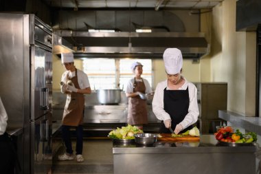 Üniformalı çoklu öğrencilerle yemek pişirme dersinde. Yeni malzemeler hazırlıyorlar..