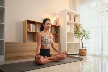 Huzur evinde yoga ve farkındalık meditasyonu yapan genç bir kadın..