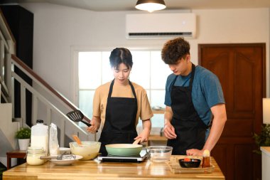 Heyecanlı çift sıcak ev mutfağında kahvaltılık krep hazırlıyor..
