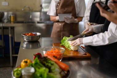 Aşçılık kursunda sebze hazırlama konusunda öğrencilere rehberlik eden aşçı..