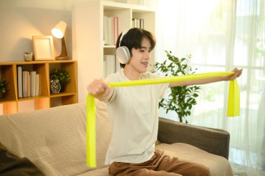 Kulaklıklı gülen adam oturma odasında direniş bandıyla çalışıyor..