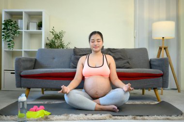 Hamile kadın doğum öncesi sağlık için evde meditasyon yapıyor..
