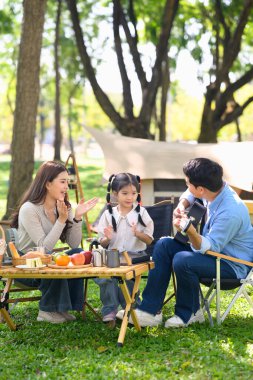 Ebeveynler ve kızları doğa ve taze yiyeceklerle çevrili bir orman parkında kamp yapıyorlar..