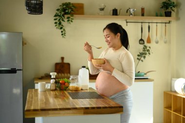 Gülümseyen hamile kadın mısır gevreği yiyor. Sağlıklı hamilelik yaşam tarzı kavramı.