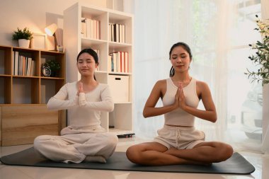 Sakin ve odaklanmış anne-kız birlikte yoga yapıyorlar..