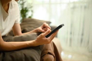 Evdeki kanepede dinlenirken akıllı telefon kullanan adama yaklaş..